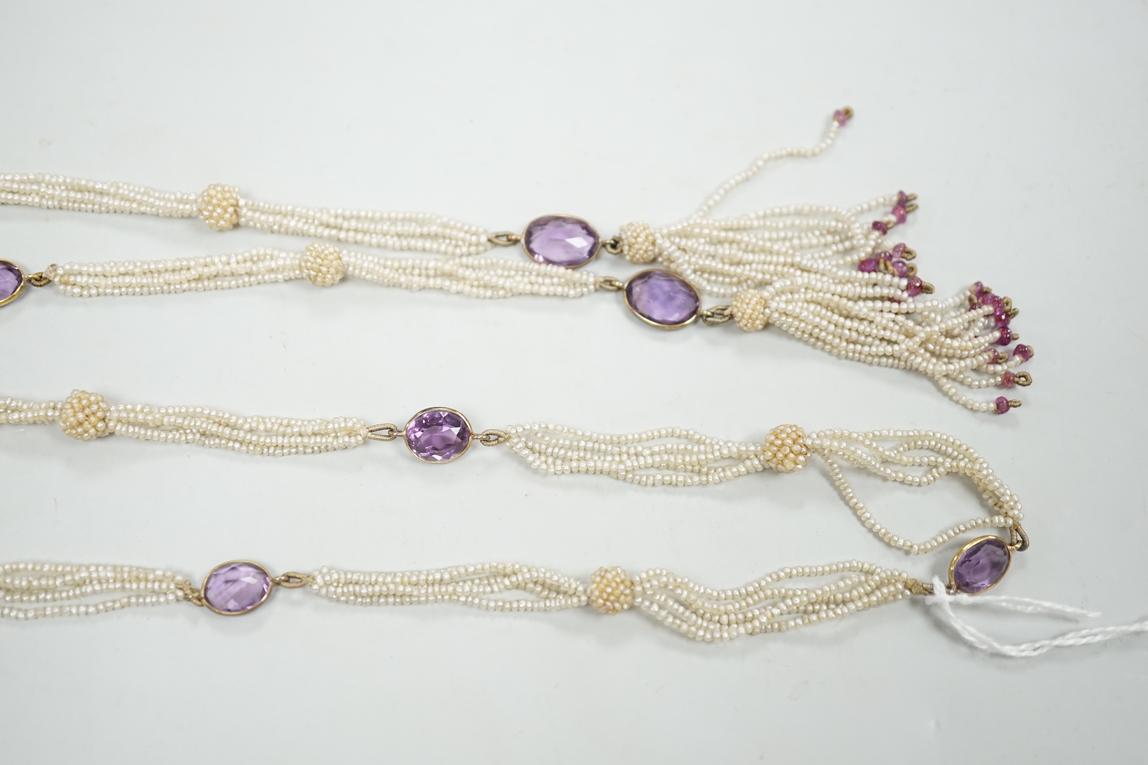 A 19th century Indian multi strand seed pearl and oval cut amethyst set long necklace, with gem set tassel drops, 166cm.